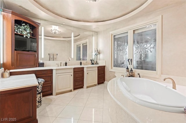 bathroom featuring vanity, tiled bath, tile patterned floors, and a tray ceiling