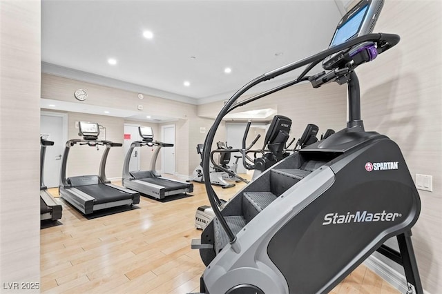 workout area with ornamental molding and light hardwood / wood-style floors