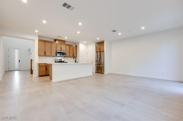 kitchen with a kitchen island with sink, sink, and stainless steel appliances