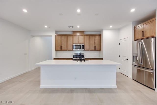 kitchen with stainless steel appliances, sink, and an island with sink