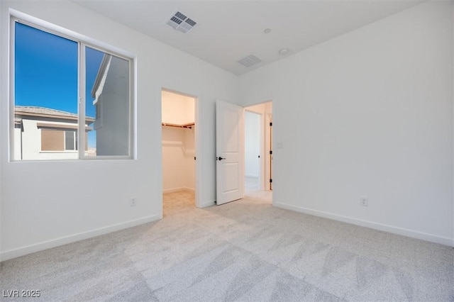 unfurnished bedroom featuring light carpet, a spacious closet, and a closet