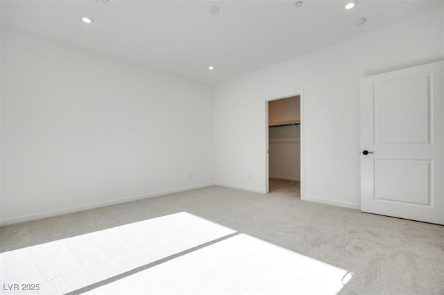 unfurnished bedroom featuring a spacious closet, light colored carpet, and a closet