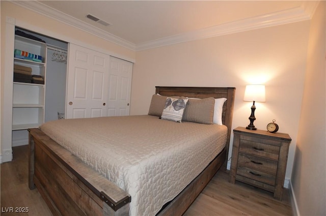 bedroom featuring wood-type flooring, ornamental molding, and a closet