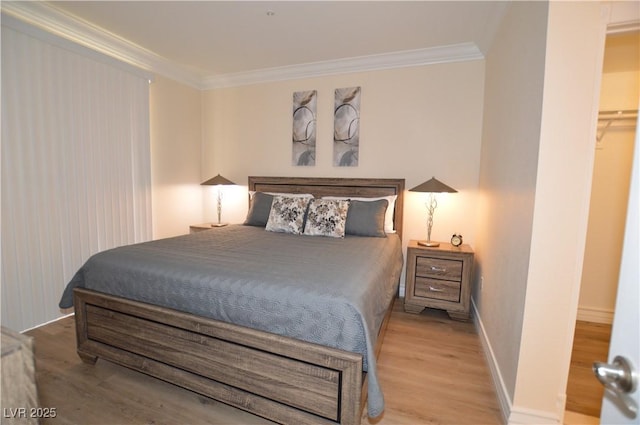 bedroom with crown molding, a walk in closet, hardwood / wood-style floors, and a closet