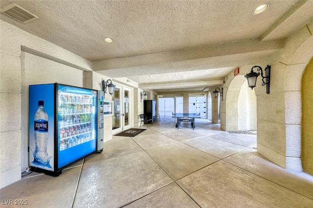 hallway with wine cooler, concrete floors, french doors, and a textured ceiling