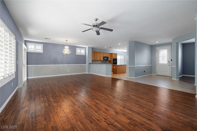 unfurnished living room with ceiling fan with notable chandelier and hardwood / wood-style floors