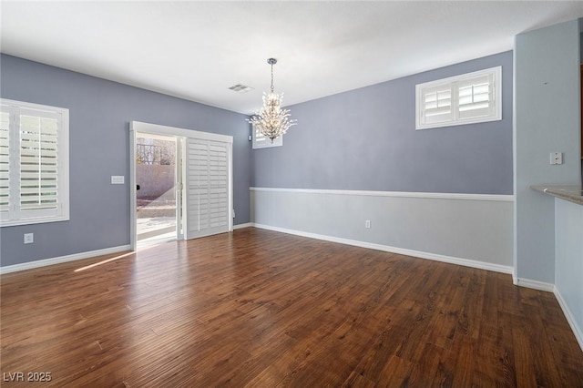 unfurnished dining area with dark hardwood / wood-style flooring, a notable chandelier, and plenty of natural light