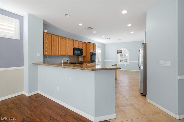 kitchen featuring stone countertops, decorative light fixtures, kitchen peninsula, and black appliances