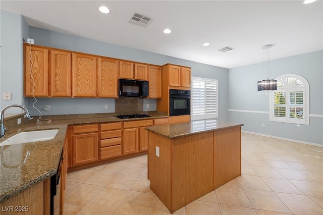 kitchen featuring sink, hanging light fixtures, a kitchen island, dark stone counters, and black appliances