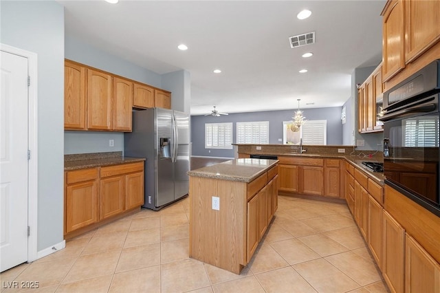 kitchen featuring light tile patterned floors, appliances with stainless steel finishes, hanging light fixtures, a center island, and kitchen peninsula