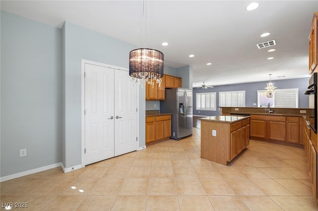 kitchen with stainless steel refrigerator with ice dispenser, sink, decorative light fixtures, a center island, and light tile patterned floors