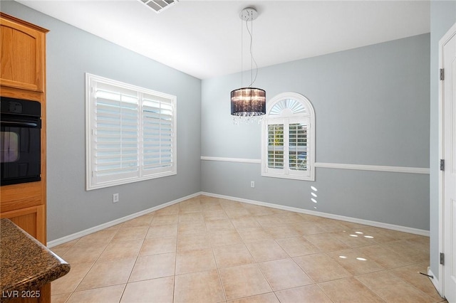 unfurnished dining area with a chandelier and light tile patterned flooring