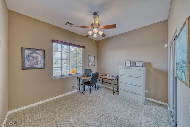 office area featuring baseboards, visible vents, ceiling fan, and light colored carpet