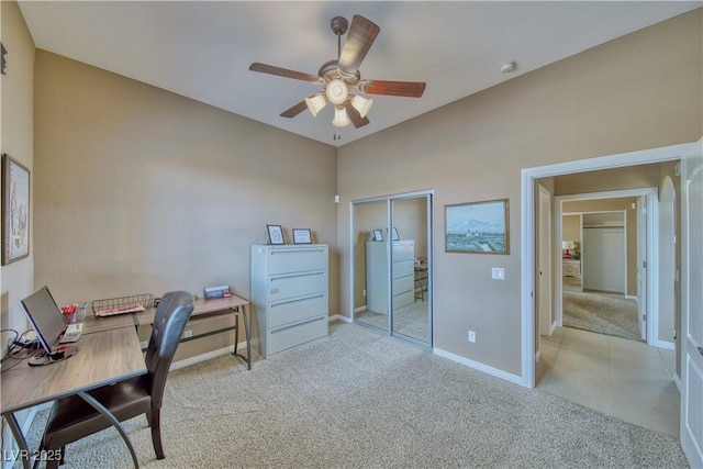 office space with baseboards, a ceiling fan, and light colored carpet