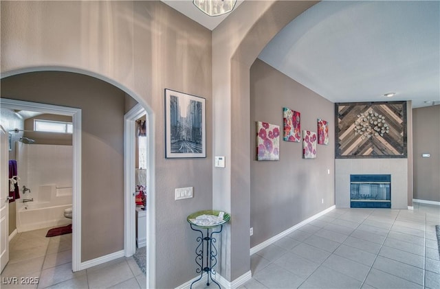 interior space with arched walkways, light tile patterned flooring, and baseboards