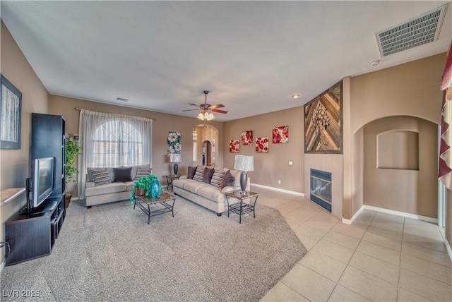 living room with arched walkways, visible vents, light tile patterned flooring, and a tile fireplace