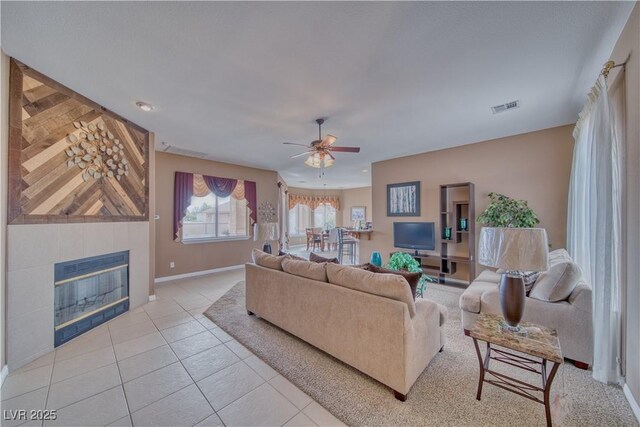 living room with a tile fireplace, heating unit, light tile patterned floors, and ceiling fan