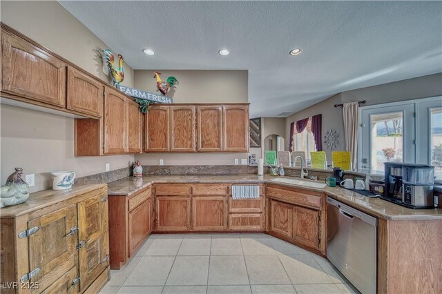 kitchen featuring sink, a textured ceiling, light tile patterned flooring, stainless steel dishwasher, and kitchen peninsula