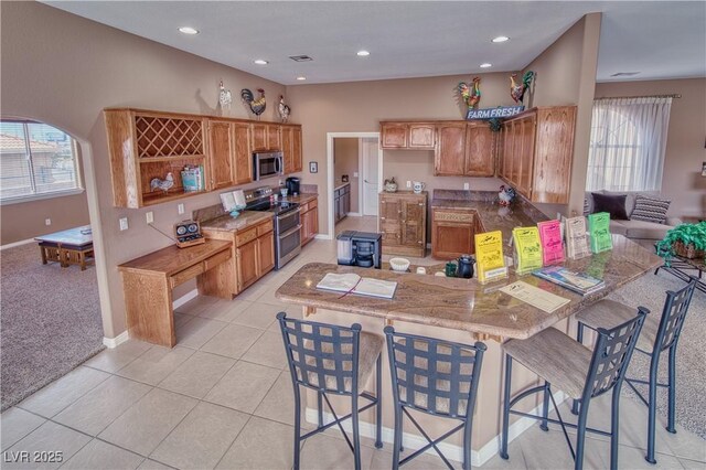 kitchen featuring appliances with stainless steel finishes, light tile patterned floors, a kitchen breakfast bar, and kitchen peninsula