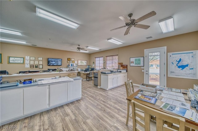 kitchen featuring plenty of natural light, white cabinets, light hardwood / wood-style floors, and kitchen peninsula