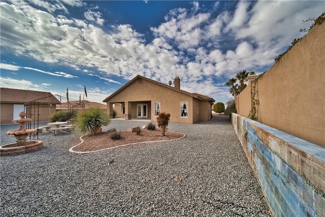 rear view of property with a patio, fence, and stucco siding