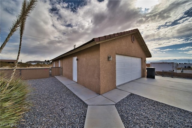 view of property exterior featuring a garage, an outbuilding, fence, and stucco siding