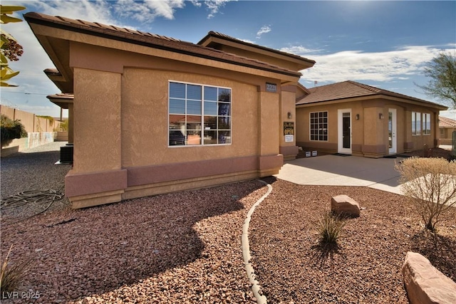 rear view of property with a patio, cooling unit, fence, and stucco siding