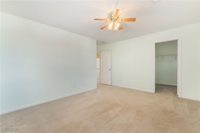 unfurnished bedroom featuring baseboards, a ceiling fan, light colored carpet, a walk in closet, and a closet