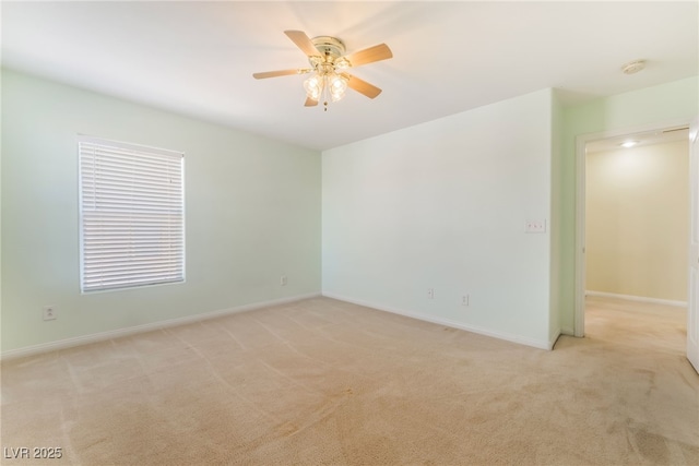 spare room with baseboards, a ceiling fan, and light colored carpet