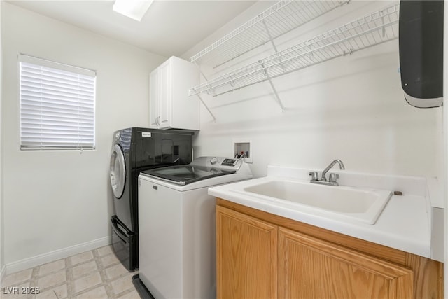 clothes washing area with light floors, washing machine and clothes dryer, cabinet space, a sink, and baseboards