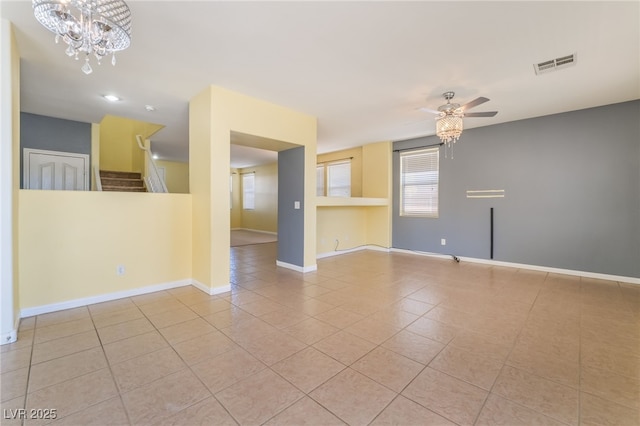 unfurnished room featuring baseboards, visible vents, tile patterned floors, stairs, and ceiling fan with notable chandelier