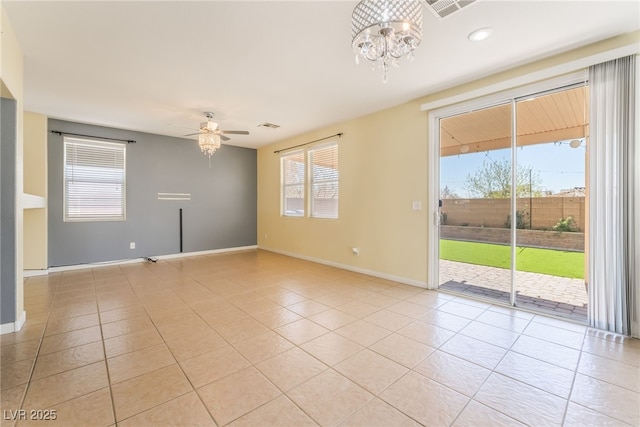 spare room featuring a healthy amount of sunlight, light tile patterned floors, baseboards, and ceiling fan with notable chandelier