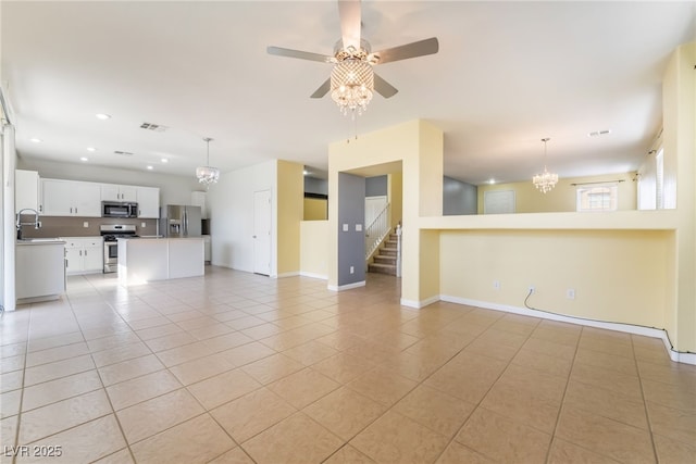 unfurnished living room featuring light tile patterned flooring, recessed lighting, ceiling fan with notable chandelier, visible vents, and baseboards