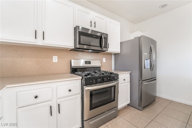 kitchen with light tile patterned floors, stainless steel appliances, white cabinets, light countertops, and decorative backsplash