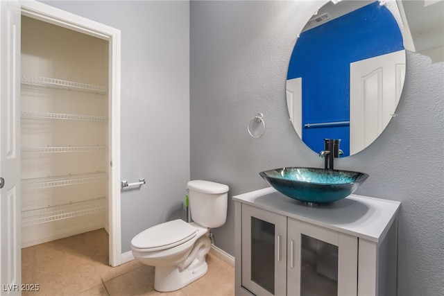 bathroom with visible vents, toilet, vanity, baseboards, and tile patterned floors