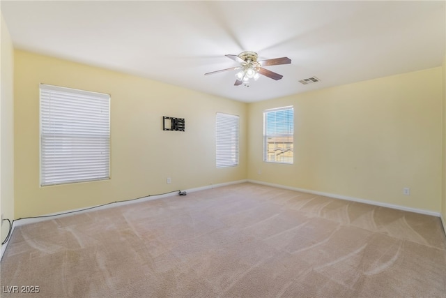 empty room with baseboards, carpet floors, visible vents, and a ceiling fan