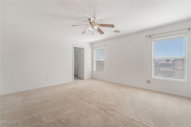 spare room with baseboards, visible vents, a ceiling fan, and light colored carpet