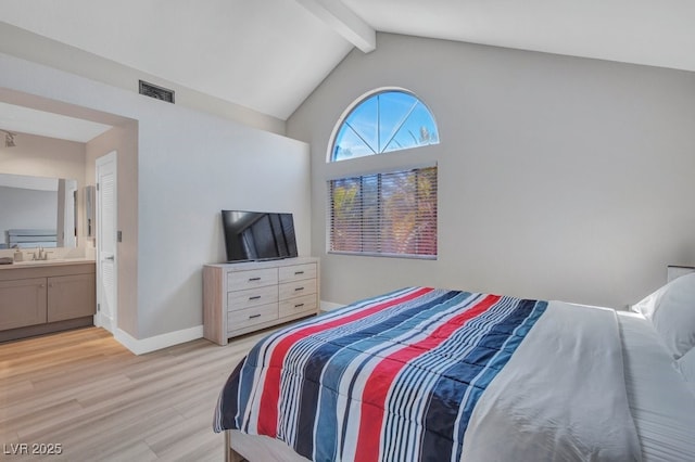 bedroom with connected bathroom, light hardwood / wood-style flooring, vaulted ceiling with beams, and sink