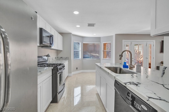 kitchen with sink, plenty of natural light, light stone counters, black appliances, and white cabinets