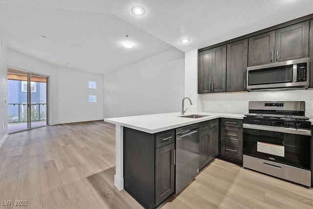 kitchen featuring sink, stainless steel appliances, dark brown cabinetry, kitchen peninsula, and light wood-type flooring