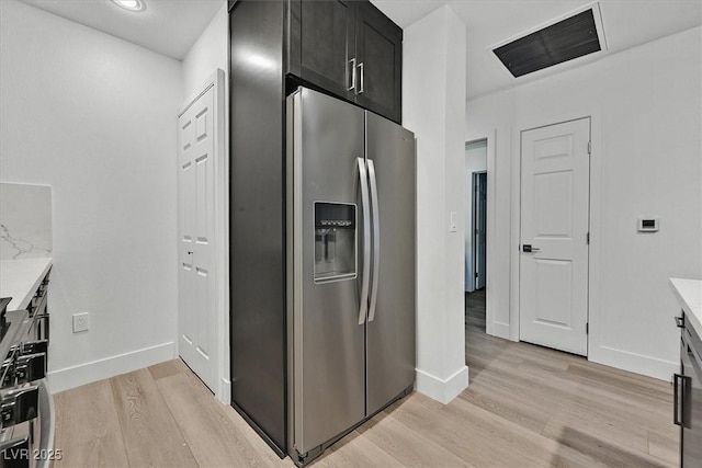 kitchen featuring light stone countertops, stainless steel fridge, and light hardwood / wood-style flooring