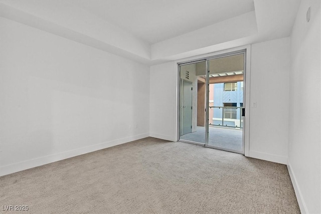 carpeted spare room featuring a tray ceiling