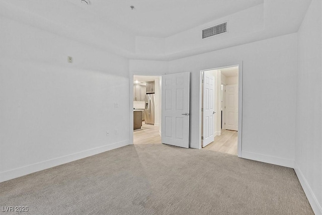 carpeted spare room with a tray ceiling