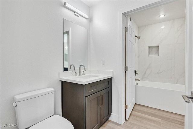 full bathroom with tiled shower / bath, wood-type flooring, toilet, and vanity