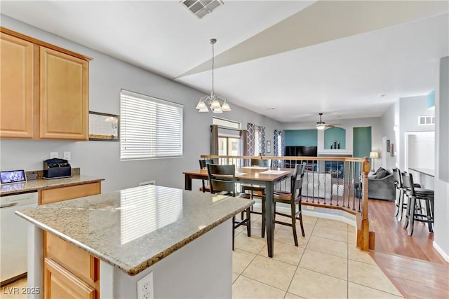 kitchen with decorative light fixtures, light brown cabinets, white dishwasher, a kitchen island, and ceiling fan with notable chandelier