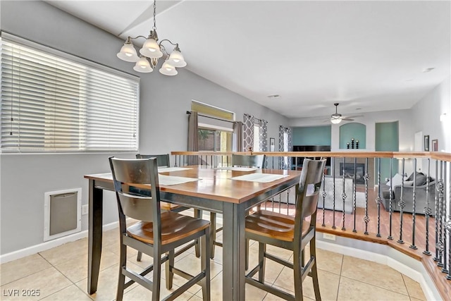 tiled dining room featuring ceiling fan with notable chandelier