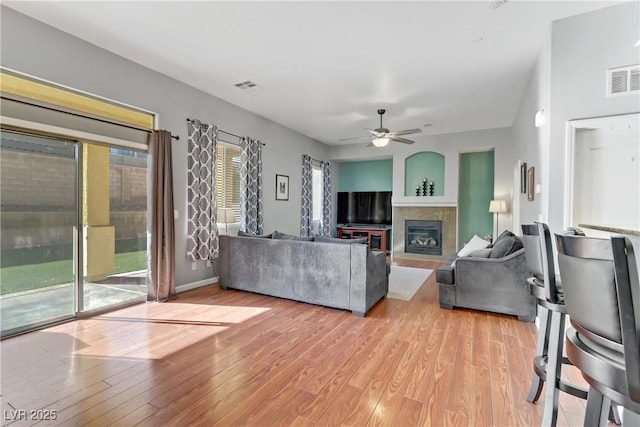 living room with a fireplace, ceiling fan, and light wood-type flooring