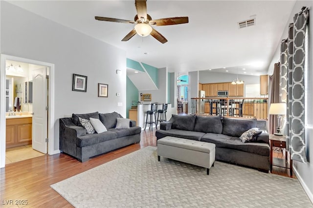 living room with wood-type flooring and ceiling fan with notable chandelier