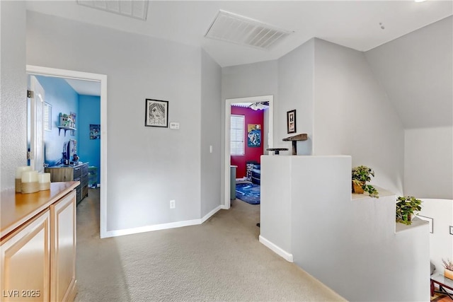 hallway featuring vaulted ceiling and light colored carpet