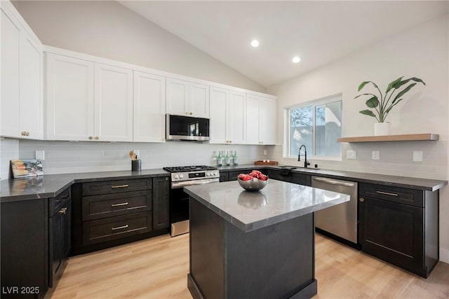 kitchen featuring tasteful backsplash, white cabinetry, a center island, stainless steel appliances, and light wood-type flooring